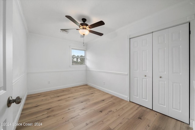 unfurnished bedroom with ceiling fan, ornamental molding, light hardwood / wood-style floors, and a closet