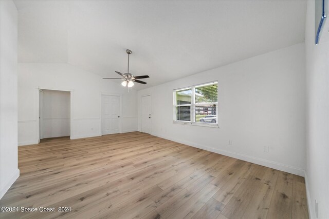 empty room with ceiling fan, light hardwood / wood-style floors, and vaulted ceiling