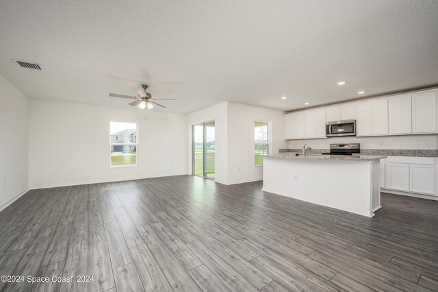 kitchen featuring white cabinets, an island with sink, appliances with stainless steel finishes, wood-type flooring, and sink