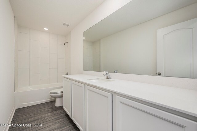 full bathroom with vanity, hardwood / wood-style floors, tiled shower / bath combo, and toilet