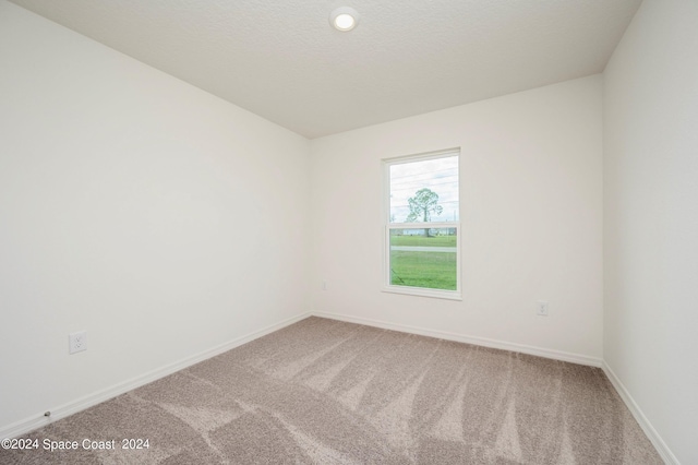 empty room featuring a textured ceiling, carpet, and baseboards