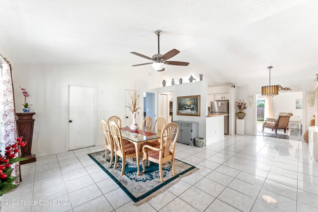 tiled dining room with ceiling fan with notable chandelier and vaulted ceiling