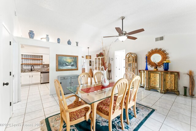 tiled dining space with ceiling fan, high vaulted ceiling, a textured ceiling, and sink