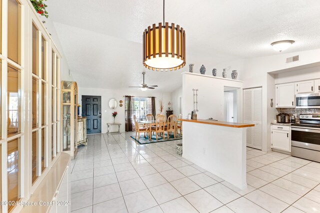 kitchen with white cabinets, light tile patterned floors, backsplash, and stainless steel appliances