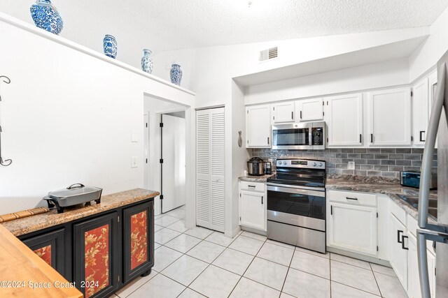 kitchen with appliances with stainless steel finishes, white cabinets, and lofted ceiling