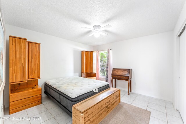 bedroom with a textured ceiling, ceiling fan, and light tile patterned flooring