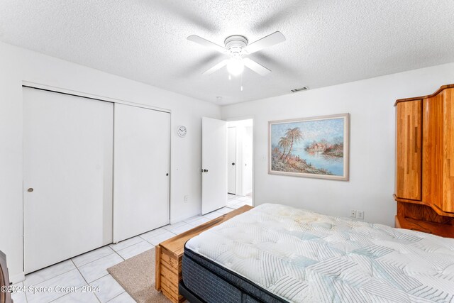 tiled bedroom with ceiling fan and a textured ceiling