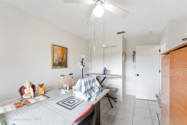 interior space with ceiling fan, light tile patterned flooring, and a textured ceiling