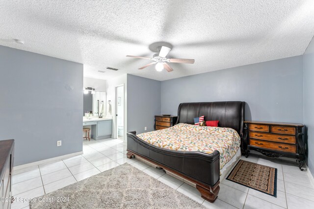 tiled bedroom with a textured ceiling, ceiling fan, and connected bathroom