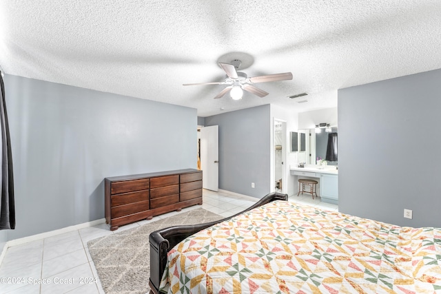 tiled bedroom with a textured ceiling, ceiling fan, and ensuite bathroom