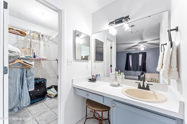 bathroom with a textured ceiling, ceiling fan, tile patterned flooring, and vanity