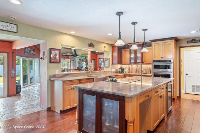 kitchen with a center island, backsplash, black electric stovetop, sink, and hanging light fixtures