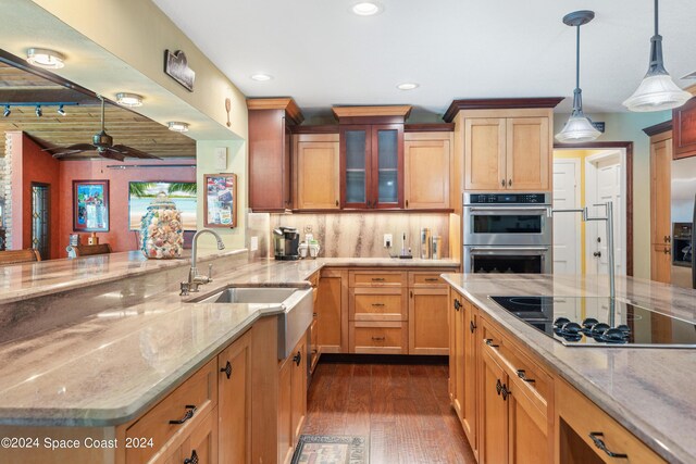 kitchen featuring light stone counters, cooktop, stainless steel double oven, sink, and pendant lighting