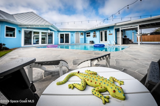 view of swimming pool featuring a jacuzzi, a patio, and french doors