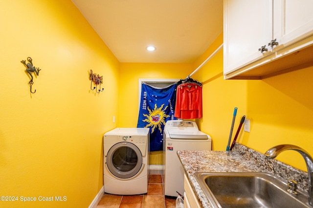 washroom with cabinets, light tile patterned floors, washing machine and dryer, and sink