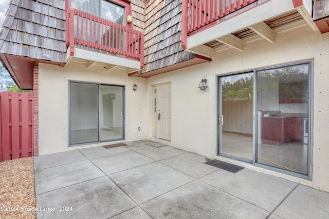 view of exterior entry featuring a patio area and a balcony