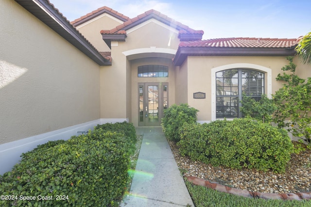 doorway to property featuring a tiled roof, french doors, and stucco siding