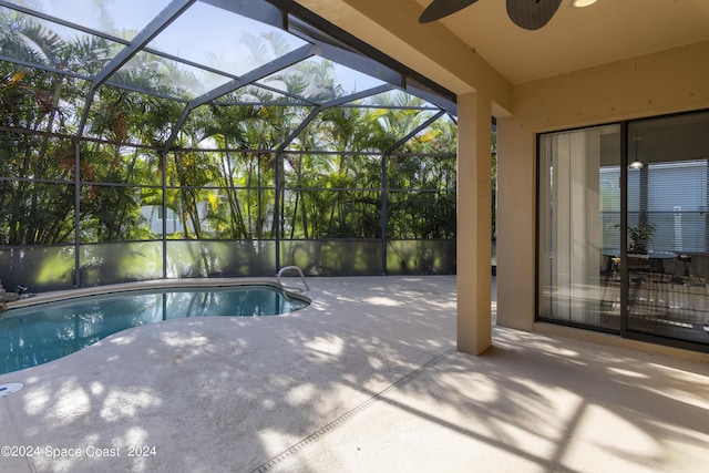 pool with a patio area, glass enclosure, and a ceiling fan