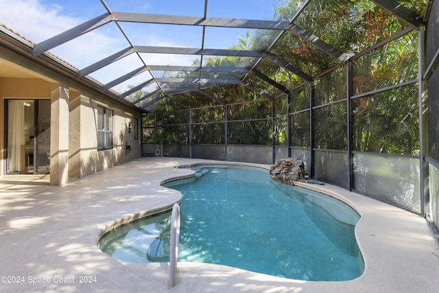 pool featuring glass enclosure and a patio area