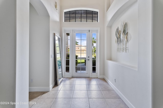 tiled entryway with a towering ceiling, baseboards, and arched walkways