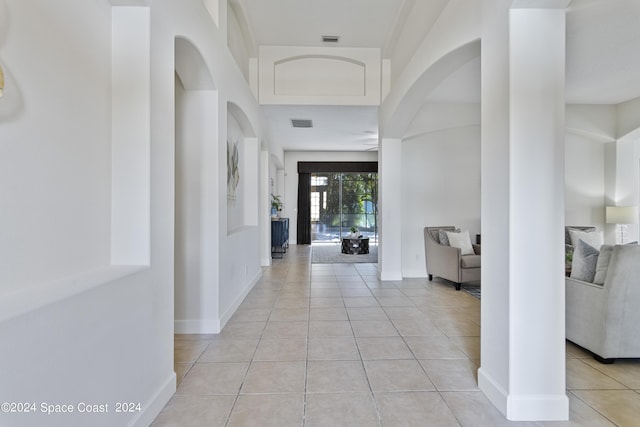 hall featuring baseboards, visible vents, and light tile patterned flooring