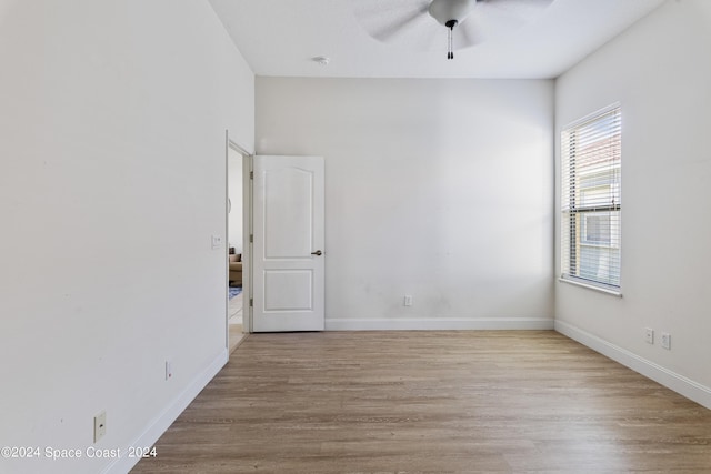 unfurnished room with wood finished floors, a ceiling fan, and baseboards