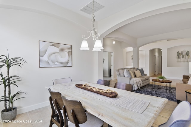 dining space featuring arched walkways, visible vents, baseboards, and light tile patterned floors