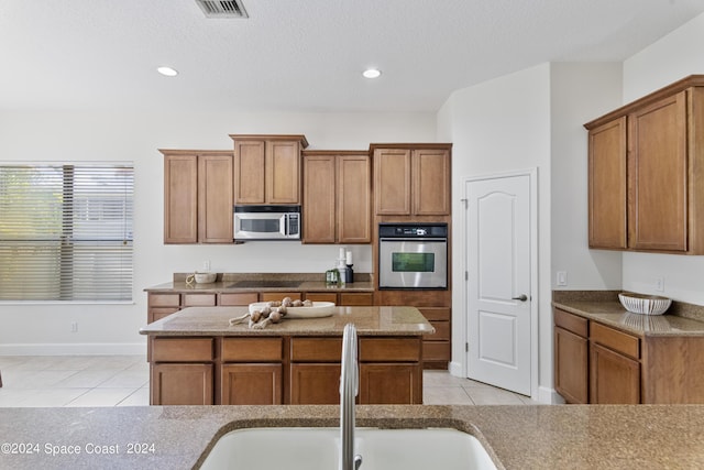 kitchen featuring appliances with stainless steel finishes, brown cabinets, and a sink