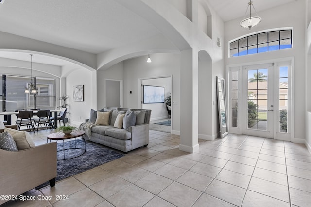 foyer featuring an inviting chandelier, a high ceiling, baseboards, and light tile patterned floors