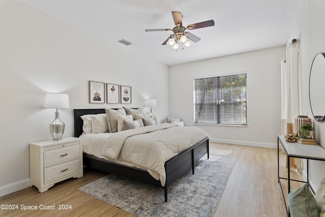 bedroom with light wood finished floors, visible vents, and baseboards