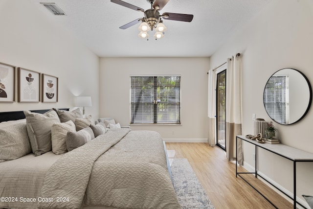 bedroom featuring light wood-style floors, baseboards, visible vents, and a textured ceiling