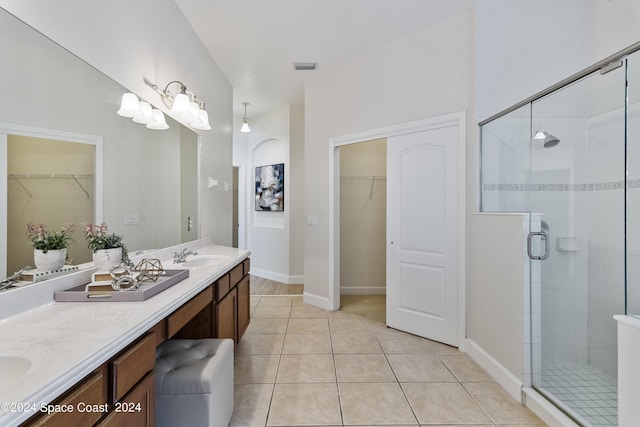 full bath featuring double vanity, a stall shower, a walk in closet, and tile patterned floors