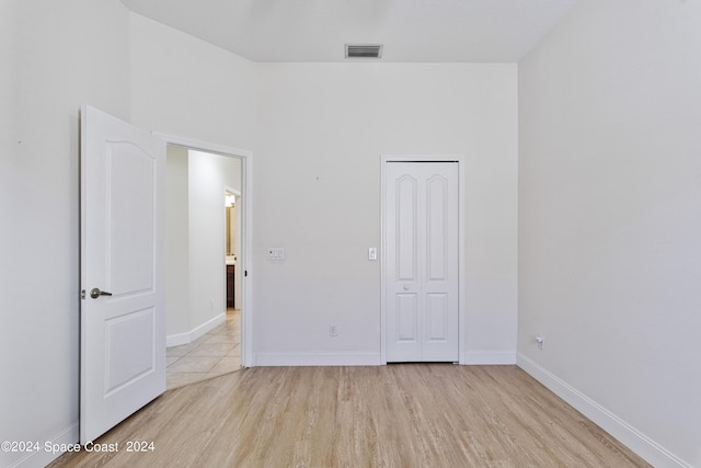 unfurnished bedroom featuring a closet, visible vents, baseboards, and wood finished floors