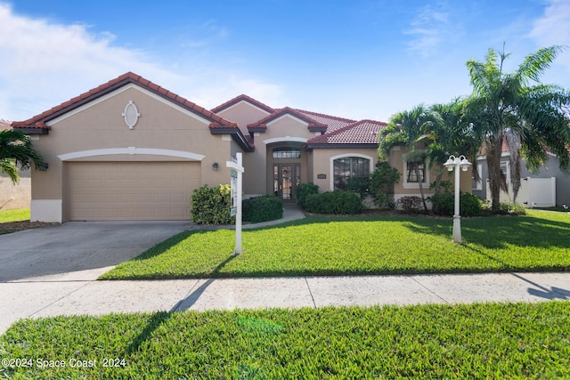 mediterranean / spanish-style house featuring a garage, concrete driveway, stucco siding, a tile roof, and a front yard