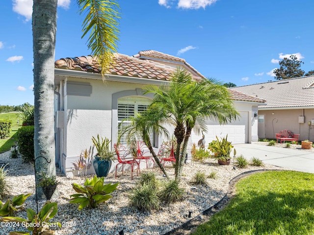 view of front of home with a garage, concrete driveway, a tiled roof, and stucco siding