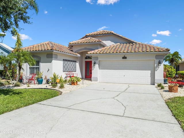 mediterranean / spanish-style house featuring a garage, driveway, a tiled roof, and stucco siding