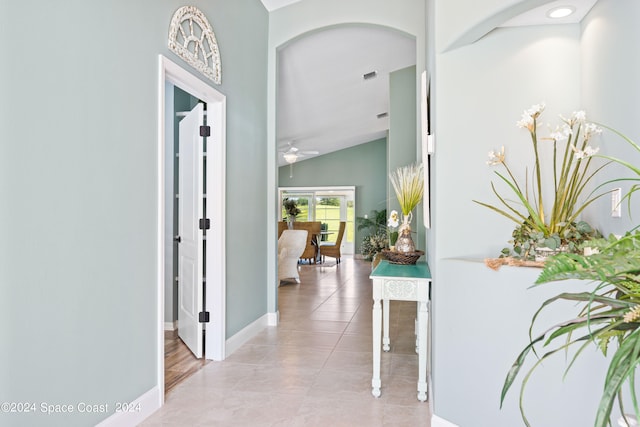 hall with light tile patterned floors, baseboards, and vaulted ceiling