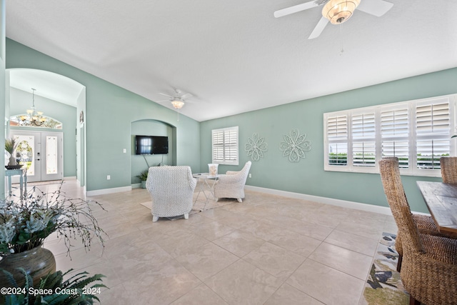 living room with baseboards, arched walkways, vaulted ceiling, and ceiling fan with notable chandelier