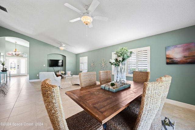 dining area with arched walkways, light tile patterned floors, vaulted ceiling, baseboards, and ceiling fan with notable chandelier