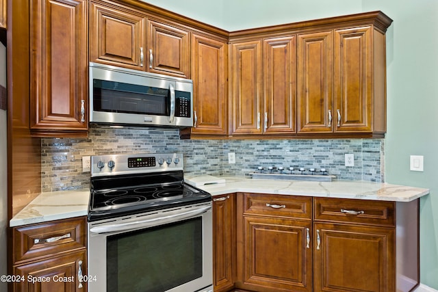 kitchen with appliances with stainless steel finishes, brown cabinetry, backsplash, and light stone countertops