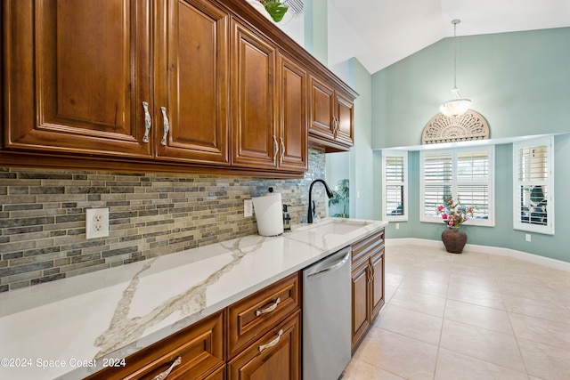 kitchen featuring light tile patterned floors, light stone counters, a sink, hanging light fixtures, and stainless steel dishwasher