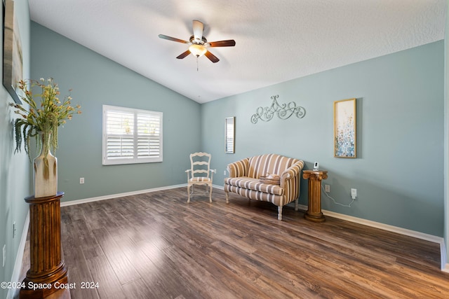 sitting room with baseboards, a ceiling fan, dark wood-style flooring, vaulted ceiling, and a textured ceiling