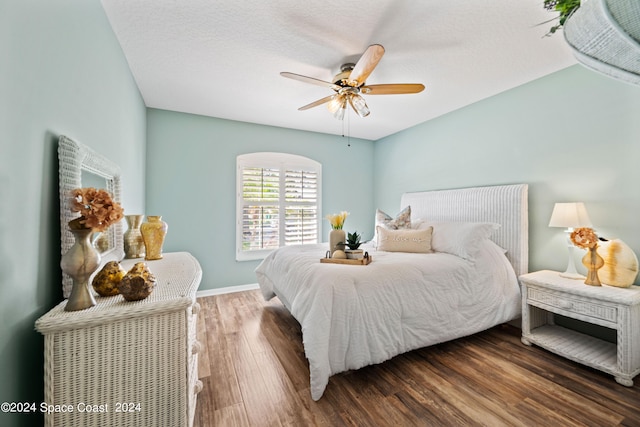 bedroom featuring ceiling fan, baseboards, dark wood finished floors, and a textured ceiling