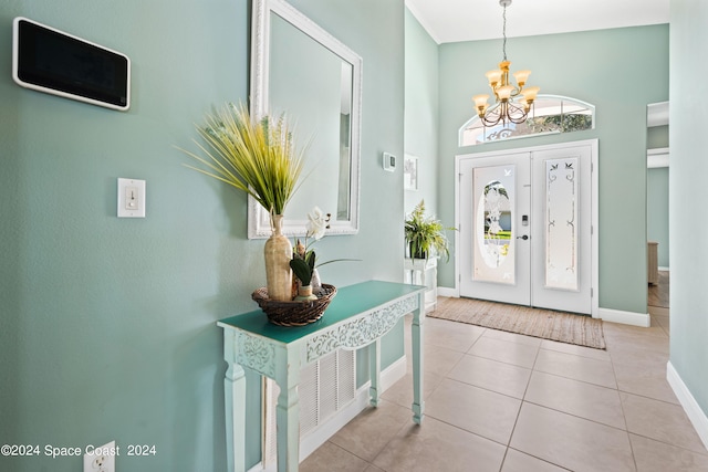 foyer entrance with a notable chandelier, a towering ceiling, baseboards, and light tile patterned floors