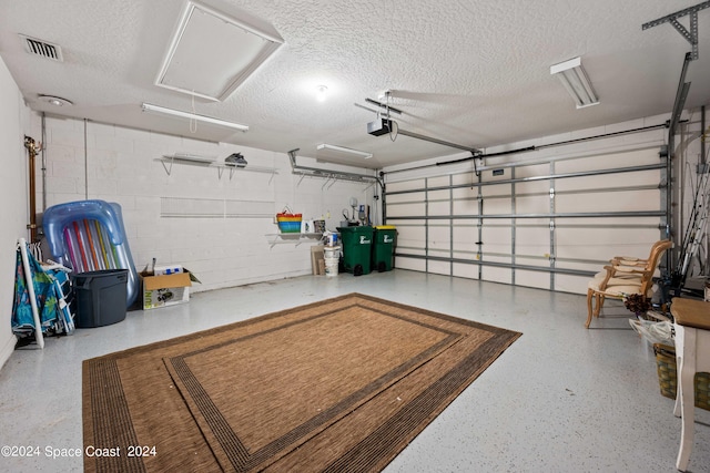 garage with visible vents, concrete block wall, and a garage door opener