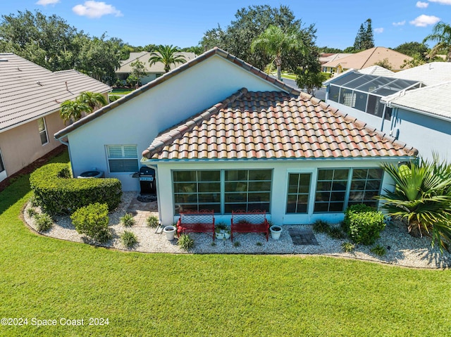 back of house with a yard, a tiled roof, and stucco siding