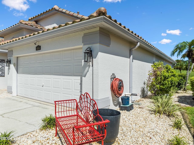 view of home's exterior featuring driveway, an attached garage, a tiled roof, and stucco siding