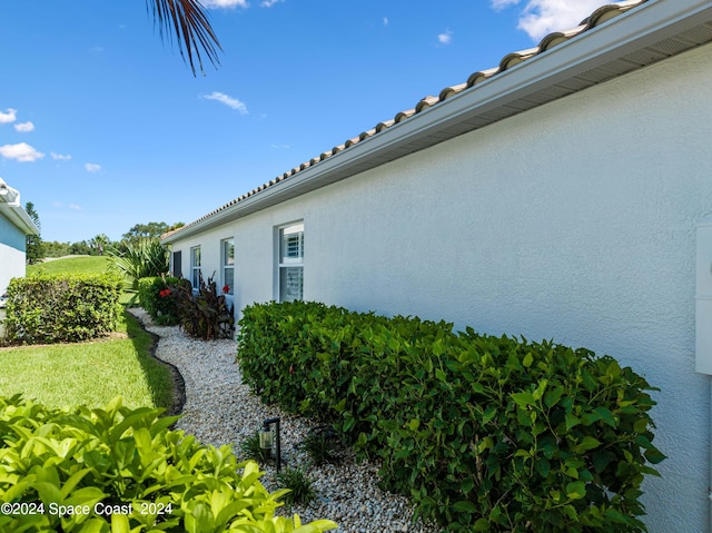 view of side of property with a tiled roof and stucco siding