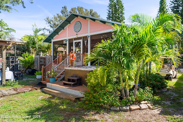 view of front of house with a sunroom, a hot tub, and a deck