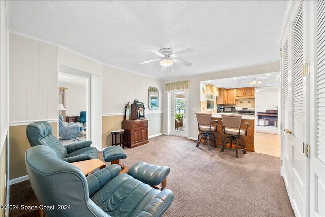 carpeted living room featuring a textured ceiling, ceiling fan, and crown molding